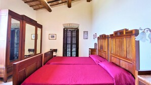 A bedroom with a wooden bed, a large mirror, a wooden wardrobe, and a ceiling fan. - Elegant Retreat in Umbria (Assisi)
