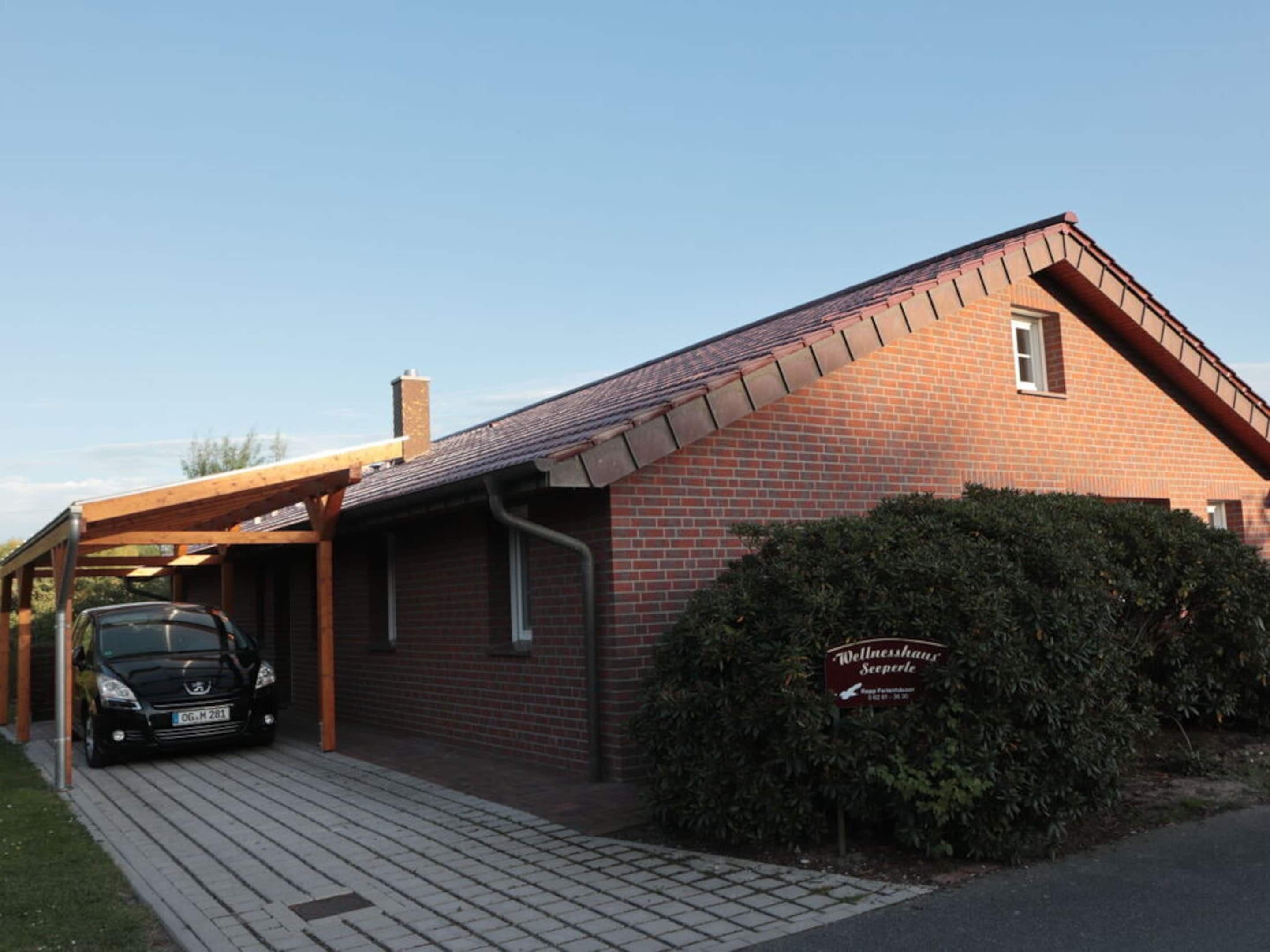 A brick building with a car parked in a covered parking area.