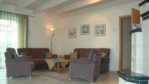 Un salon comprenant un canapé, une table basse et un lampadaire. Trois tableaux encadrés sont accrochés au mur.