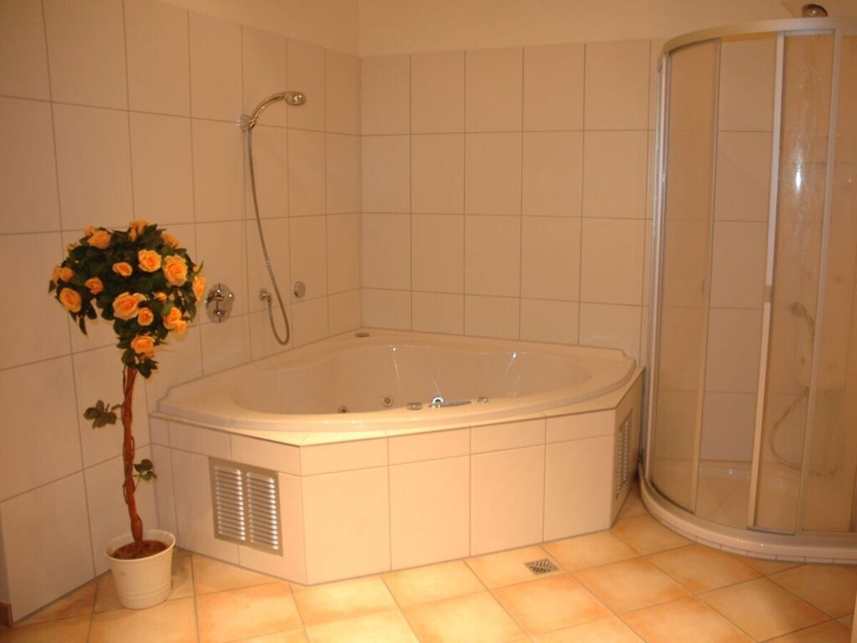 Un baño con bañera, ducha y una planta en maceta.