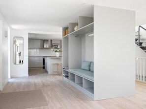 A modern kitchen with white cabinets, a microwave, and a small island with stools.
