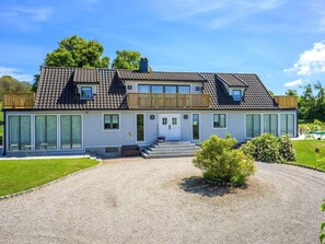 A two-story house with a large front porch, a swimming pool, and a well-maintained lawn. - 5 Star Holiday Home in Bastad (Bastad)