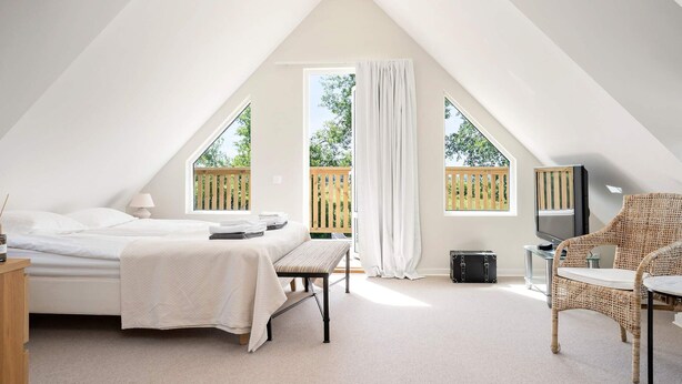 A bedroom with a bed, bedside table, chair, and a television. - 5 Star Holiday Home in Bastad (Bastad)