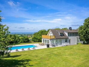 Une maison avec une piscine, un patio couvert et une vue sur le paysage.