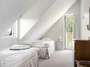 A bedroom with two beds, a bedside table, a lamp, a window, and a view of the outdoors. - 5 Star Holiday Home in Bastad (Bastad)