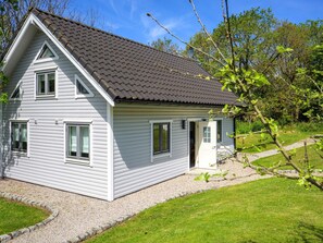 Ett tvåvåningshus med ett sluttande tak, en grusuppfart och en gräsplätt.