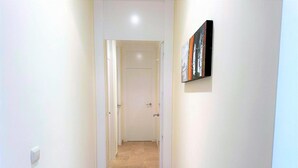A narrow hallway with beige carpet, white walls, and a door at the end.