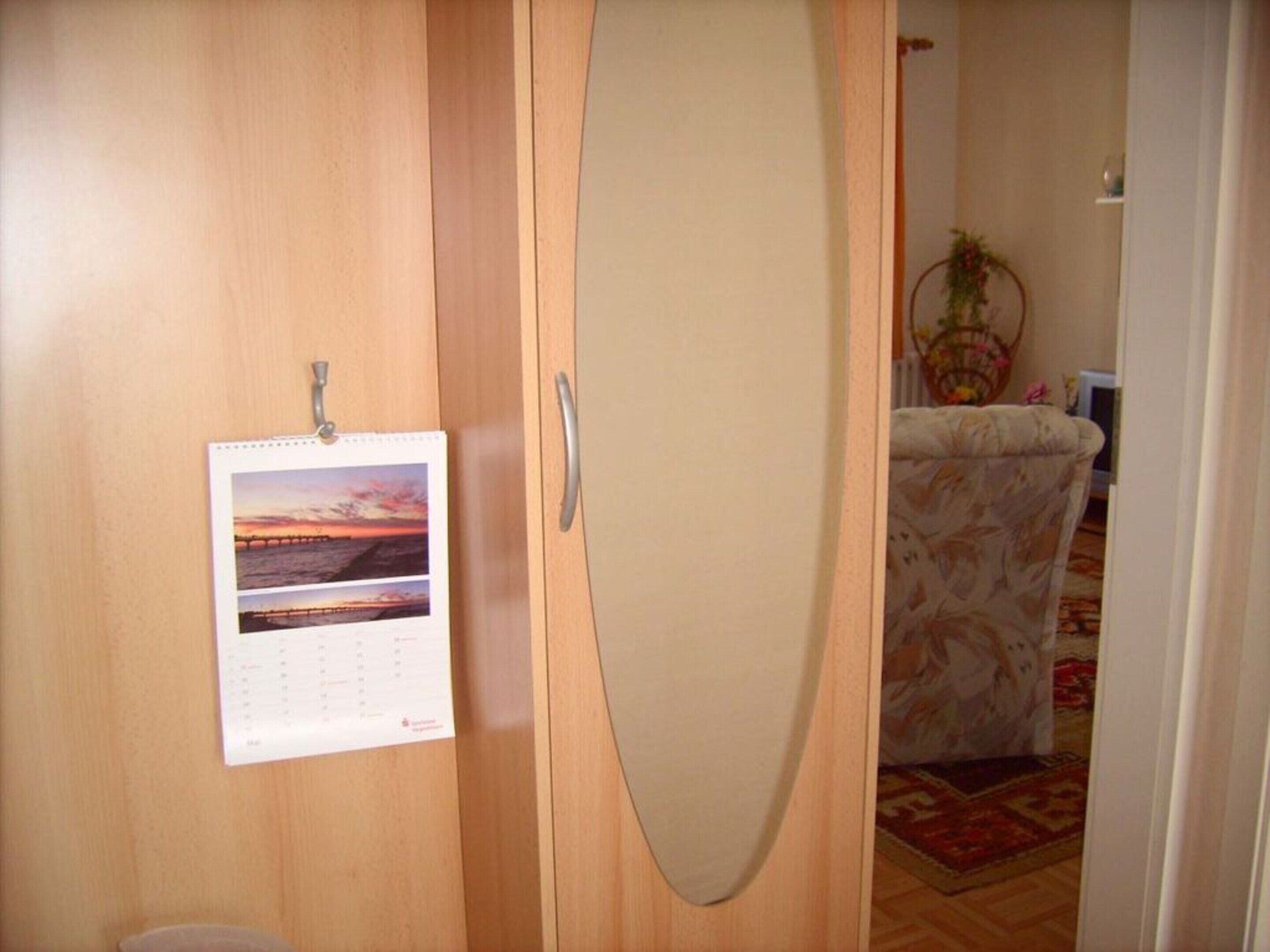 Une armoire en bois ornée d’un calendrier et d’une image représentant un coucher de soleil.
