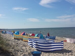 A beach with striped beach umbrellas and tents, sandy beach, and the ocean. - to the Beach Modern Retreat (Lubmin)