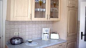 A kitchen with light wooden cabinets, a coffee maker, a toaster, and a radio on the counter. - to the Beach Modern Retreat (Lubmin)