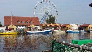 A waterfront area with a Ferris wheel, boats, and buildings. - to the Beach Modern Retreat (Lubmin)