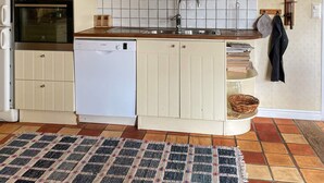 A compact kitchen with a built-in oven, microwave, and dishwasher, a sink with a faucet, and a tiled backsplash.