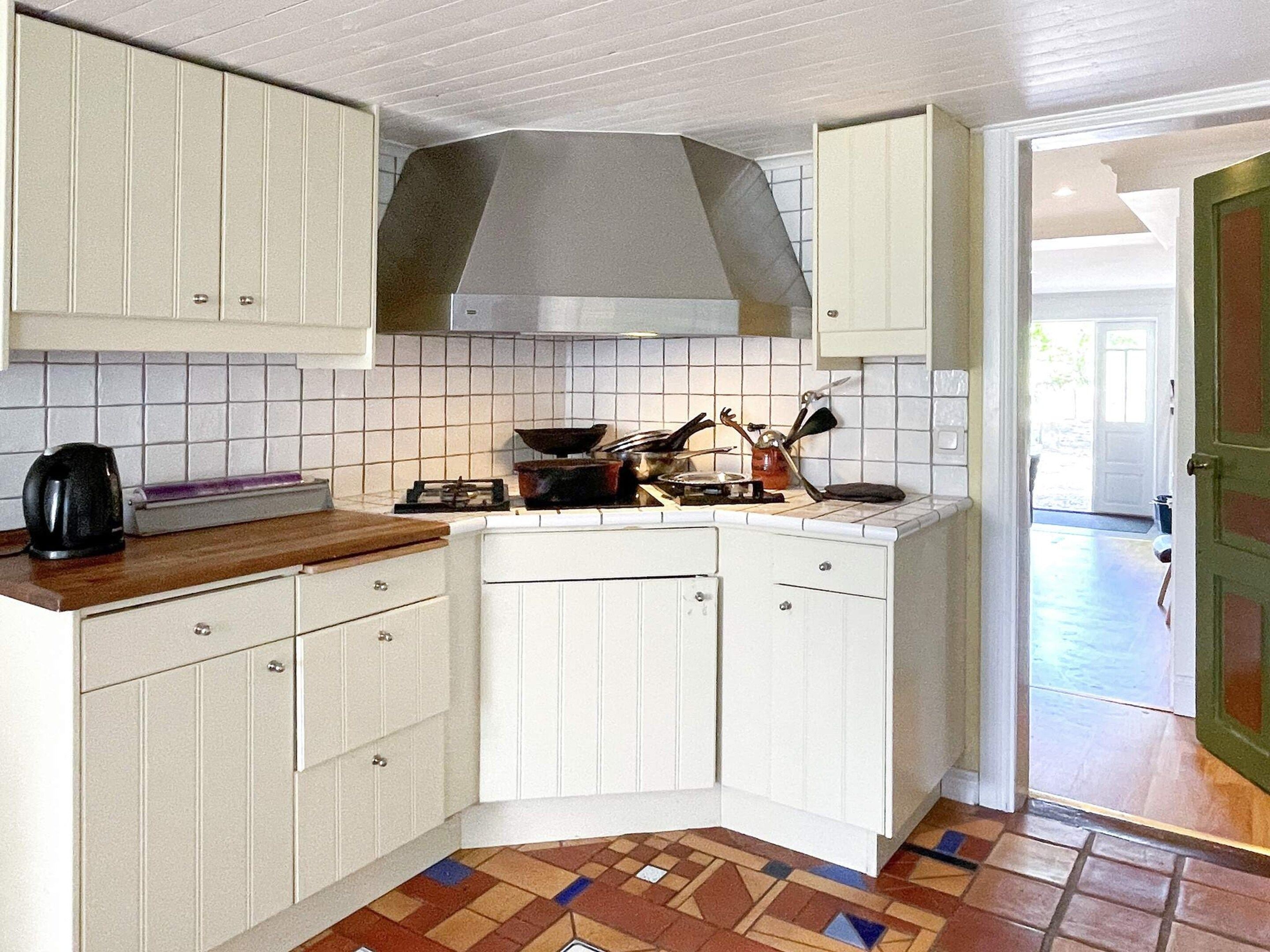 A compact kitchen with white cabinetry, a tiled backsplash, and a patterned floor.