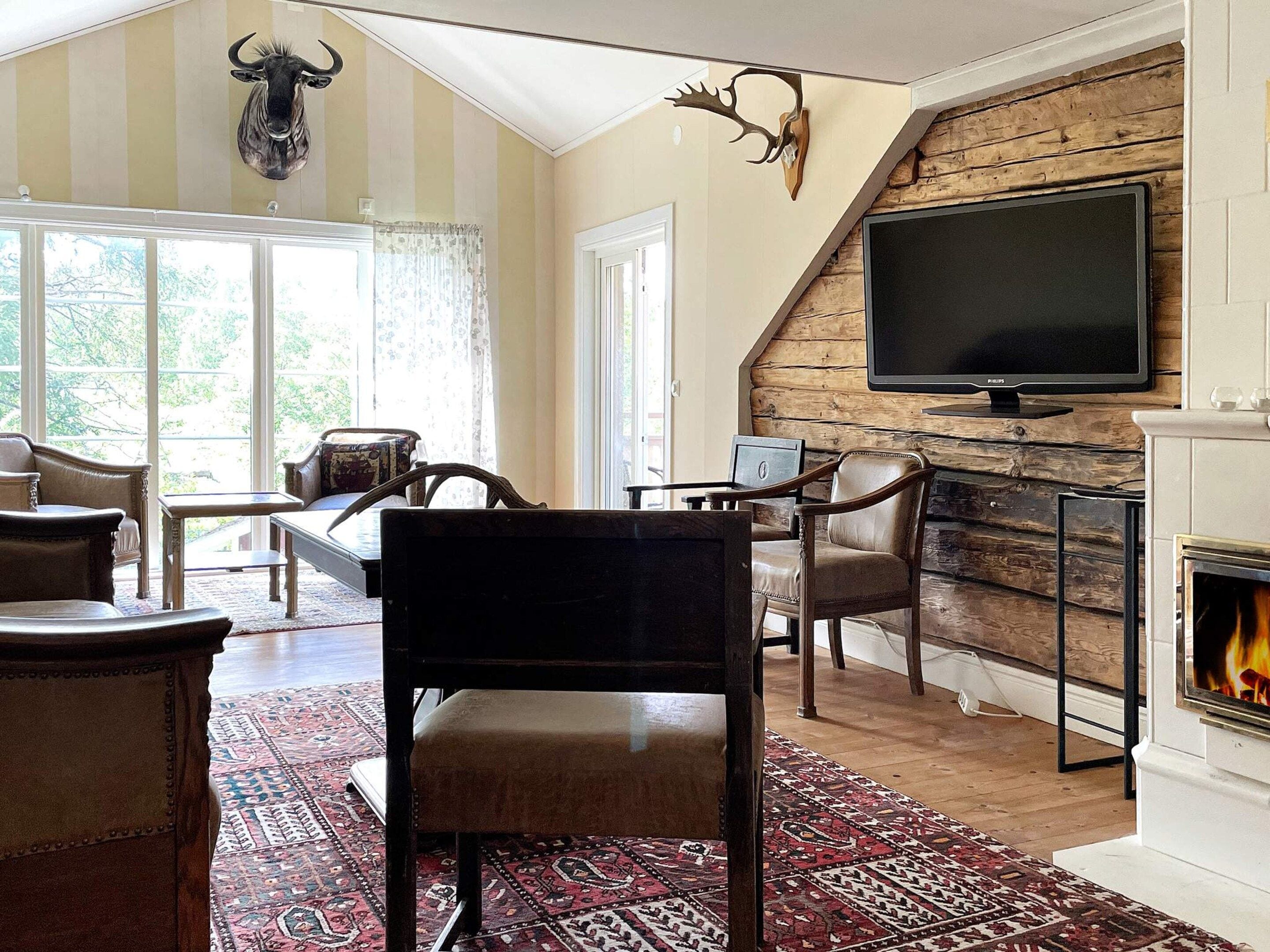 Una sala de estar con chimenea, televisor y un amplio ventanal.