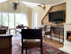 A living room with a fireplace, a television, and a large window. - 5 Star Holiday Home in Odeshog (Odeshog)