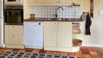 A compact kitchen with a built-in dishwasher, a microwave, and a sink with a faucet.