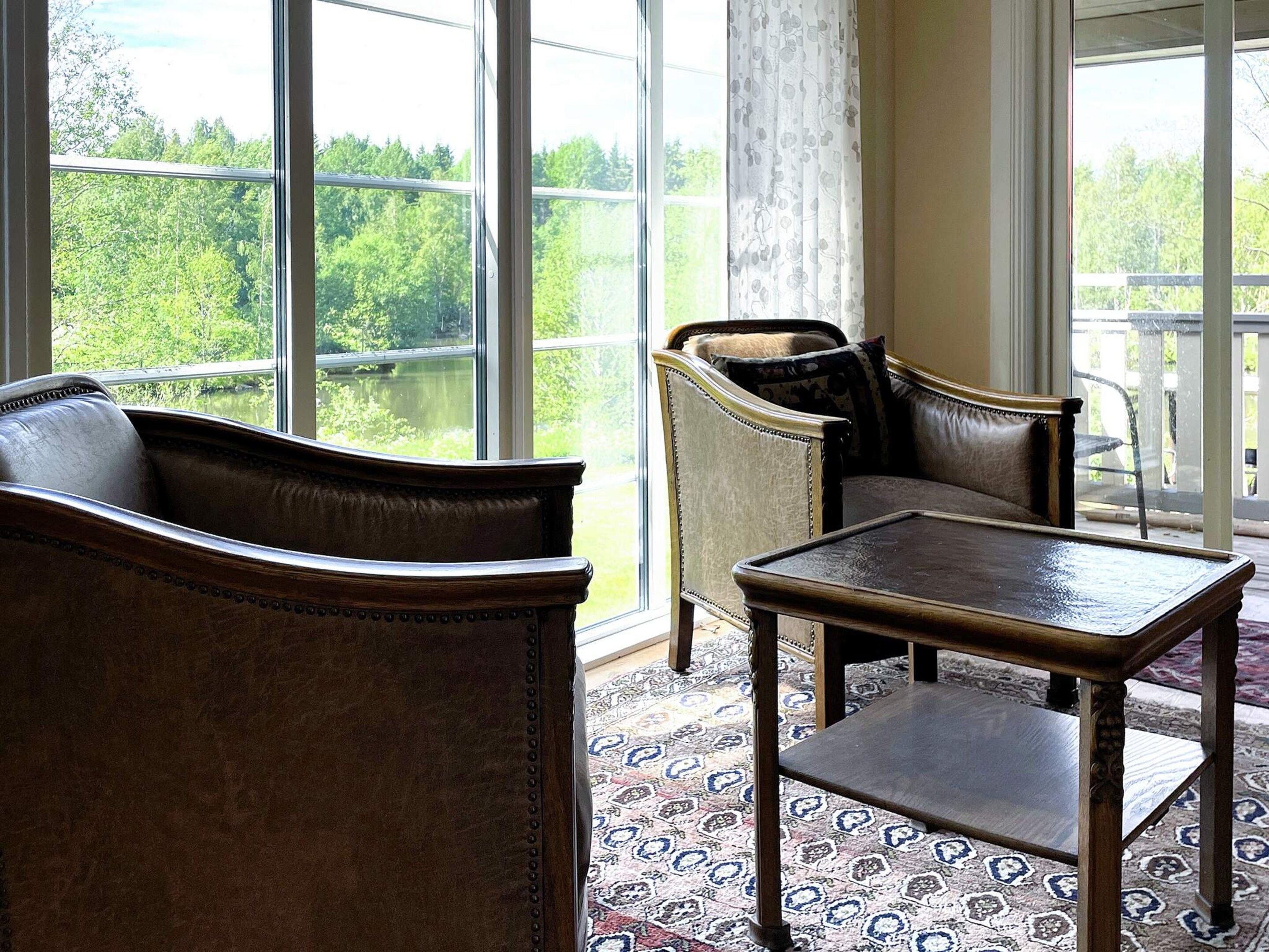 A room with a large window, a sofa, a chair, and a small table.