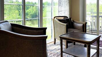 A room with a large window, a sofa, a chair, and a small table.