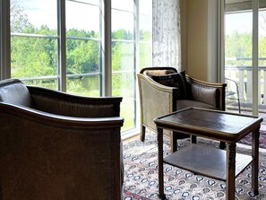 A room with a large window, a sofa, a chair, and a small table.