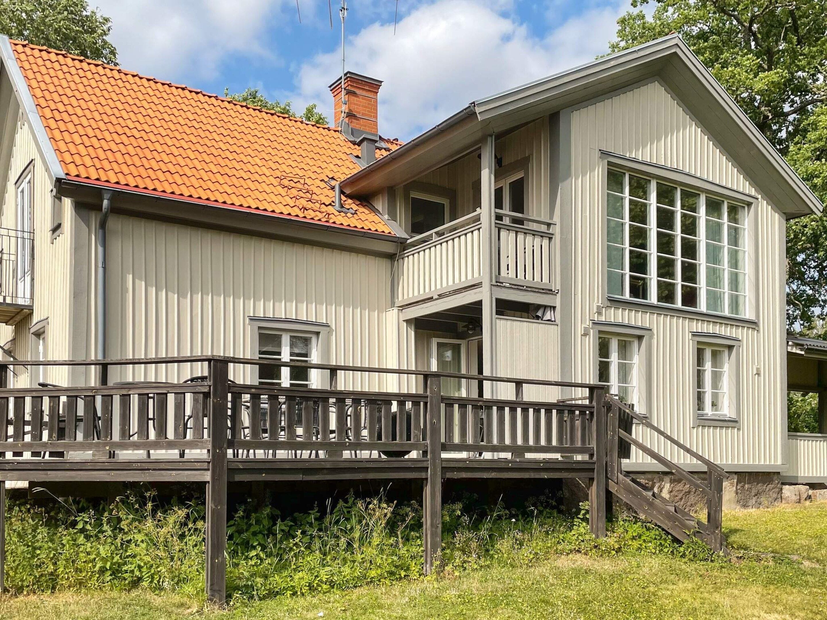 A two-story building with a red-tiled roof, a balcony, and a wooden deck.