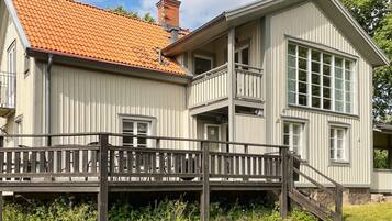 A two-story building with a red-tiled roof, a balcony, and a wooden deck.