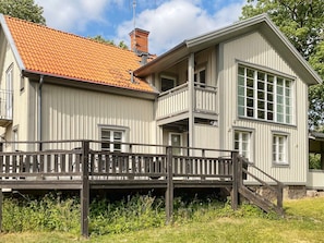 A two-story building with a red-tiled roof, a balcony, and a wooden deck. - 5 Star Holiday Home in Odeshog (Odeshog)