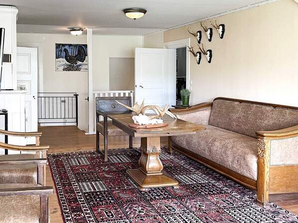 A living room with a patterned rug, a wooden coffee table, a sofa, and a wall-mounted deer head decoration. - 5 Star Holiday Home in Odeshog (Odeshog)