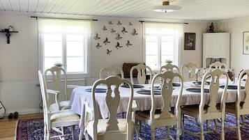 A dining area with white chairs and a table, a patterned rug, and a wall with bird decorations.