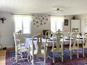 A dining area with white chairs and a table, a patterned rug, and a wall with bird decorations. - 5 Star Holiday Home in Odeshog (Odeshog)