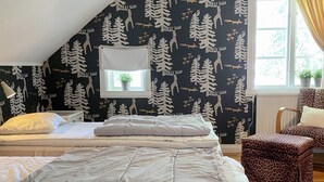 A bedroom with two beds, a window with a view, and a leopard print chair.
