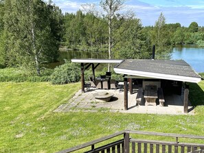 Ein Pavillon am Seeufer mit Sitzgelegenheiten im Freien und einem Feuerkorb.
