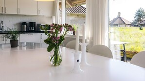 A modern kitchen with white cabinets, a large window, and a table with a vase of flowers. - 5 Person Holiday Park Home in Karrebaeksminde (Karrebæksminde)