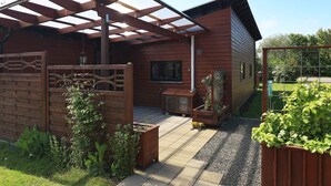 A wooden house with a covered patio, a fenced garden area, and a gravel pathway. - 6 Person Holiday Home in Vestervig (Vestervig)