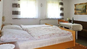 Un dormitorio con dos camas, una mesita con un florero y un cuadro en la pared.