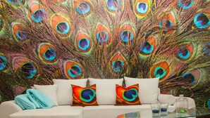 A modern living room with a white sofa, colorful peacock feather wall art, and a glass coffee table. - Kickelhahn Comfortable Holiday Residence (Geratal)