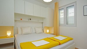 A bedroom with a bed, two bedside tables, a window with blinds, and a ceiling light. - Holiday Apartment Beach House Iva App. 3 (Gradac)