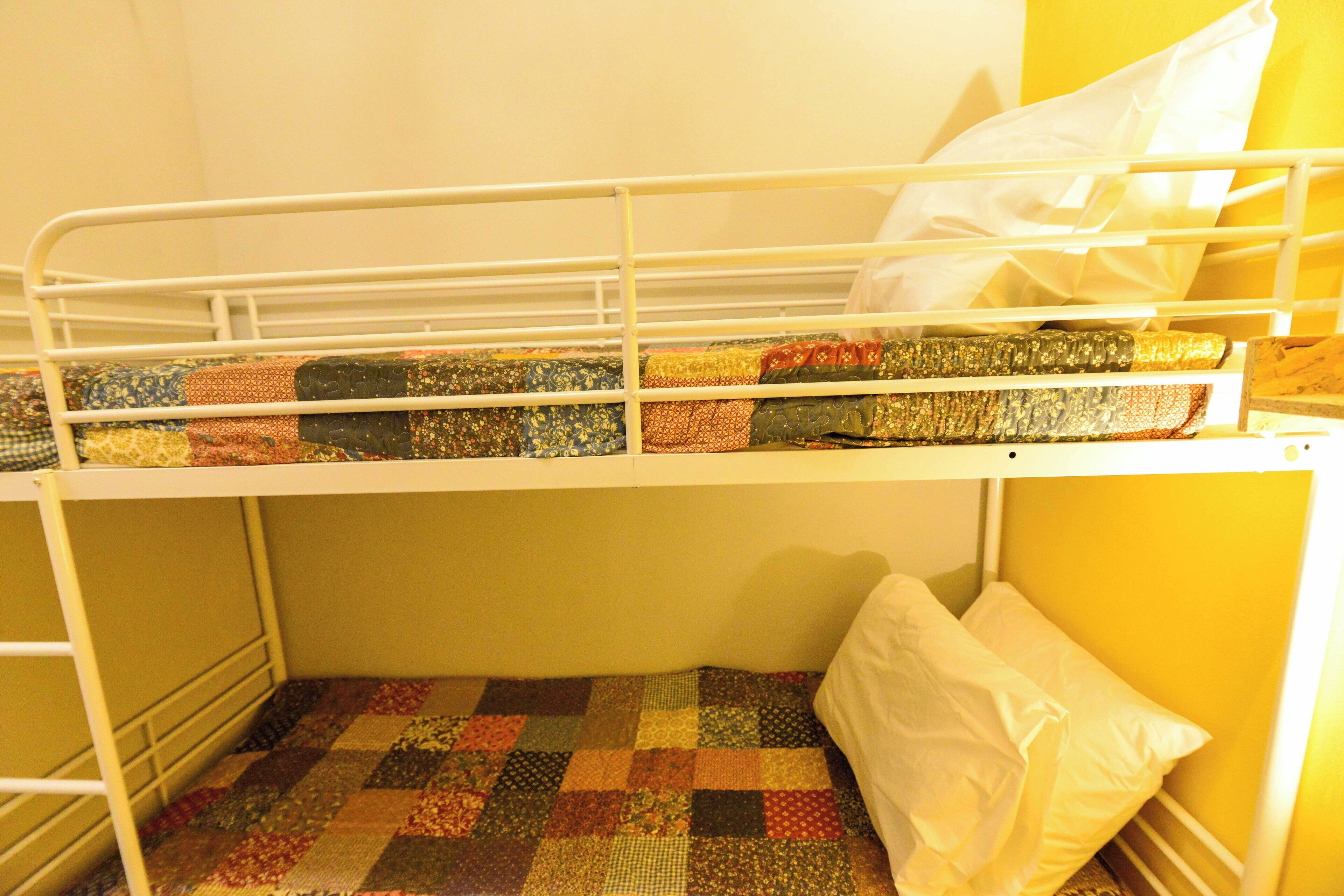 Una cama individual en literas con colchón acolchado y almohada blanca.