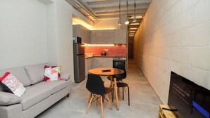 A compact kitchen with a dining area, a sofa, and a TV.