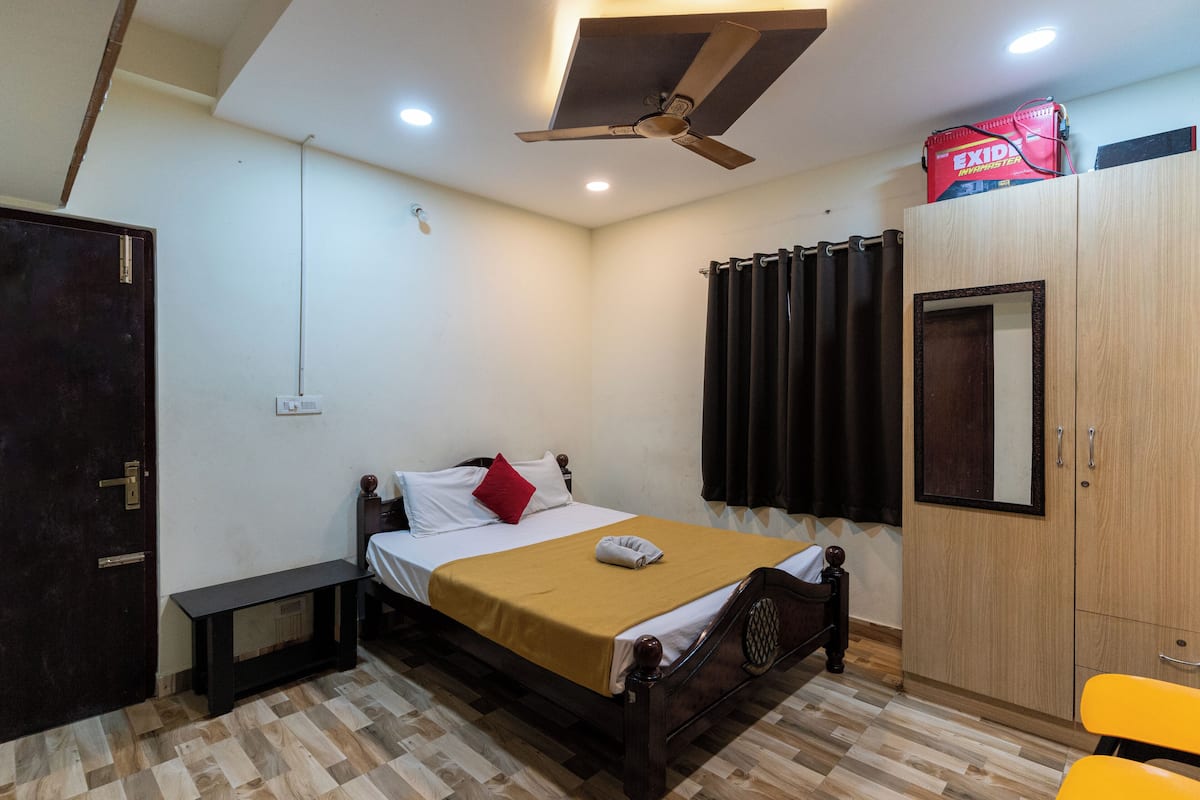 A bedroom with a bed, bedside table, wardrobe, and a ceiling fan.