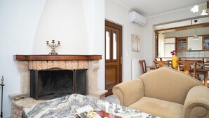 A living room with a fireplace, a sofa, and a dining area with a table and chairs. - Romance Dream Meteora 1 (Kalampaka, Greece)