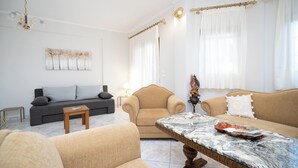 A living room with a grey sofa, a beige armchair, a marble coffee table, and a decorative vase. - Romance Dream Meteora 1 (Kalampaka, Greece)