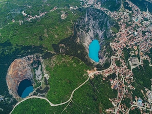 An aerial view of a town with two prominent lakes, a winding road, and a dense forest surrounding the area. - Holiday Home Dream - Holiday Home (Podbablje)