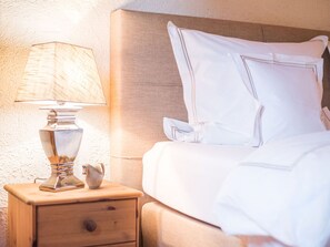 A neatly made bed with white linens and pillows, a bedside lamp, and a small wooden nightstand with a drawer. - Hans in the Schusterhausl Apartment (Samerberg)