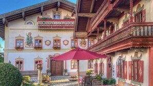 Un bâtiment traditionnel doté d’une cour pavée, de balcons en bois et d’un parasol rouge.