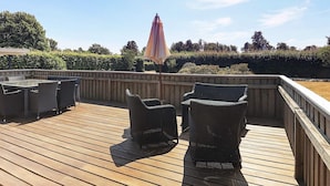 An outdoor deck with wicker furniture and a wooden railing.