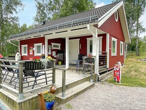 A red building with a wooden deck, outdoor seating, and a small garden area.