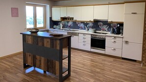 A modern kitchen with wooden flooring, white cabinets, and a central island. - Appealing Apartment Near Lake (Argenbühl)