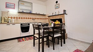 A compact kitchen with a dining area, featuring a stove, oven, and a small dining table with chairs. - Apartments Sunset - One Bedroom Apartment With Terrace and Sea View (Blato)