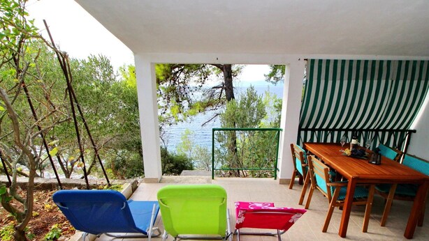 A terrace with a view of the sea, a wooden table, and three chairs. - Apartments Sunset - One Bedroom Apartment With Terrace and Sea View (Blato)