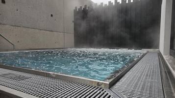 Relax in a hot tub area with a pool surrounded by a textured border and a metal ladder for easy access.